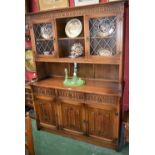 An Old Mill oak dresser, outswept cornice above a pair of glazed doors, each enclosing a shelf,