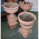 A pair of painted reconstituted garden urns, each moulded with stiff foliage,