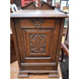 An early 20th century oak purdonium, moulded top above a fall front panel door,