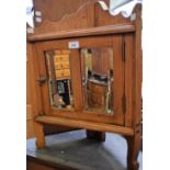 A 20th century pine corner cabinet, shaped cresting above a mirrored door, 60.