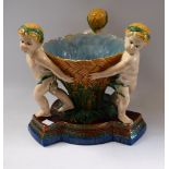 A 19th century Majolica table centrepiece, of three putti carrying a basket, Minton model no.