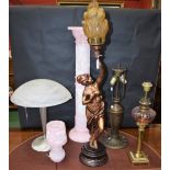 A reconstituted pink stone lamp stand and lamp; a figural lamp holding flaming torch;