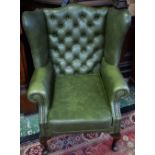 A Chesterfield type wingback armchair, deep button back, scroll arm,