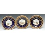 A set of three Coalport shaped circular plates, painted by P. Simpson and by J.