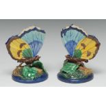 A pair of Royal Worcester majolica spill vases, as butterflies, upon leaves,