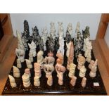 A carved stone tribal style chess set, height of king 14cm; another, Oriental style, incomplete,