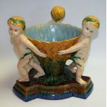 A 19th century Majolica table centrepiece, of three putti carrying a basket, Minton model no.