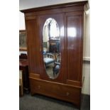 A Edwardian mahogany wardrobe, outswept cornice, over oval mirrored door flanked by panels,