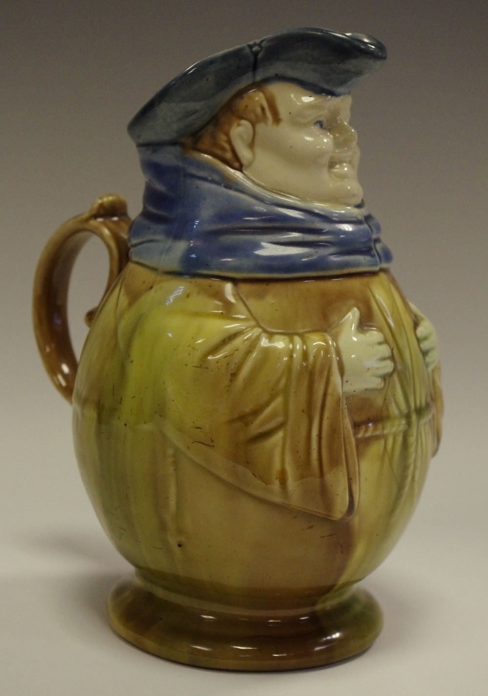 A Novelty Majolica ale Toby jug, modelled as portly gentleman, with Robe, scarf and hat,