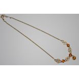 A 9ct gold and vibrant orange four stone set necklace, ornate ring and loop links,