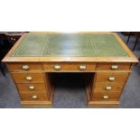 An early 20th century pitch pine tooled leather inlaid pedestal desk holding two banks of three