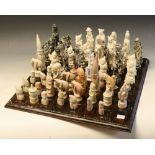 A carved stone tribal style chess set, height of king 14cm; another, Oriental style, incomplete,