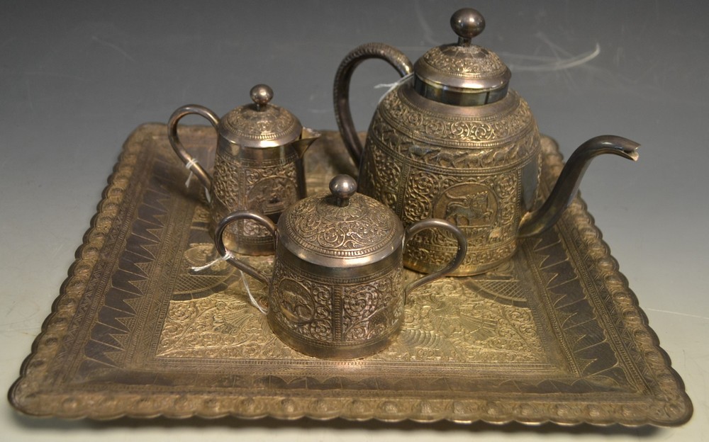 An Indian silver coloured metal three piece tea service on tray, comprising teapot,