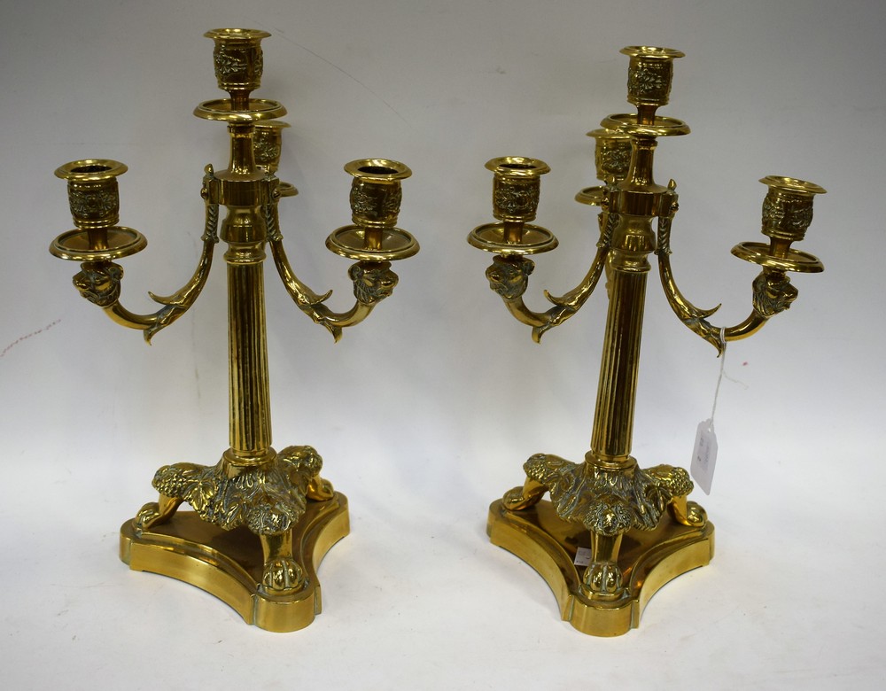 A pair of brass three branch table candlesticks, lion mask supports,