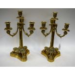 A pair of brass three branch table candlesticks, lion mask supports,