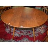 An Ercol elm dropleaf dining table, elliptical top with fall leaves,