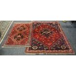 A Persian woollen rug, with three geometrical motifs, banded geometrical borders, in red,