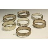 A silver bangle, hinged, chased and engraved; others,