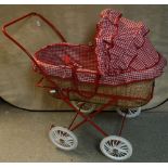 A mid-20th century wicker basket pram with red and white gingham cover and hood,