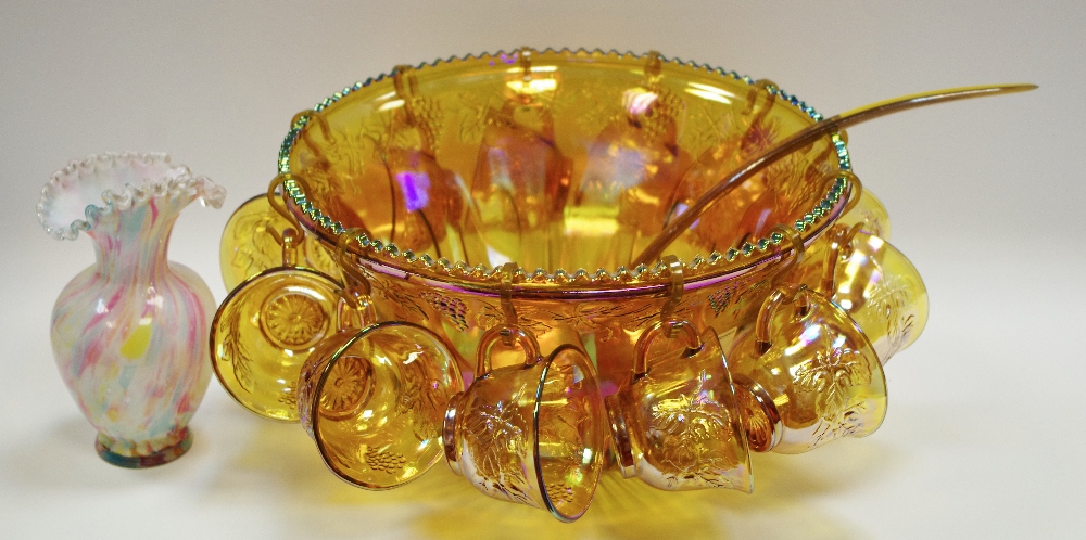 A carnival glass punch bowl, twelve cups and ladle; a mottled opaque glass vase,