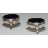 A matched pair of George III silver cauldron salts, hoof feet, blue glass liners, 6cm diam,