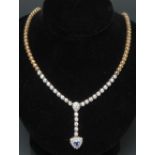 A diamond and sapphire heart pendant necklace, centrally set with a triangular shaped blue sapphire,