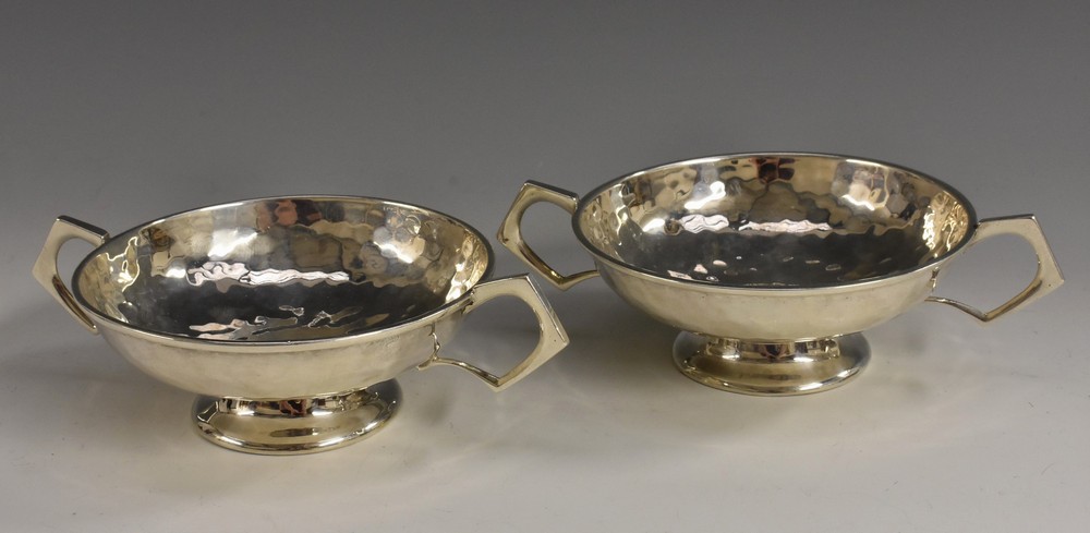 A pair of Arts and Crafts silver pedestal dishes, plainished overall, angular handles, 15cm wide,