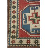 A Persian geometrical woven woollen rug, with lozenges, in tones of red, cream and blue,