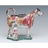 A 19th century cow creamer and cover, standing four square, with milkmaid, sponged in ochre,