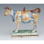 A Prattware cow creamer and cover, standing four square, sponged in ochre and blue,