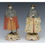 A pair of Continental pottery figures, of carnival revellers, both standing wearing tricorn hats,