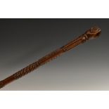 A George IV folk art gentleman's walking stick, the pommel carved as a hand grasping a mask,