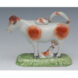 A Staffordshire cow creamer, standing four square, with calf, rust patch markings,