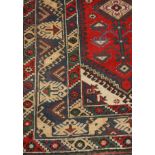 A Persian woollen rug, with central lozenge and stylised branches, banded geometrical borders,