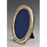 A Chinese silver oval easel photograph frame, engraved with leafy bamboo, ball feet, 17.