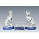 A pair of Staffordshire dalmations, seated to the the left and right, blue oval bases, 14cm high, c.