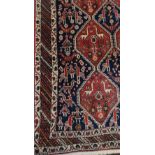 A Persian woollen rug, with stylised animals and birds with in lozenges, banded geometrical borders,