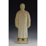 A Chinese marble figure, carved as a man in a traditional tunic and fur hat, rectangular base, 57.