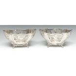 A pair of Edwardian silver lobed oval cake baskets, pierced with borders of scrolling foliage,