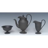 A Wedgwood three piece black basalt pedestal urnular coffee pot and cover, milk jug and sugar bowl,