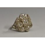 An Art Deco diamond cluster ring, central raised round brilliant cut diamond approx 0.