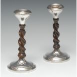 A pair of Arts and Crafts silver and oak candlesticks, shallow ogee sconces, 'barley twist' pillars,