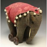 A 1930's push along felt elephant on four Bakelite wheels, bone tusks,