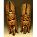 Tribal Art - a pair of graduated carved wooden wall masks, stylized elongated masks,
