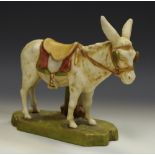 A Royal Dux model of a donkey, standing wearing a blinkered bridal and saddle, in green and brown,