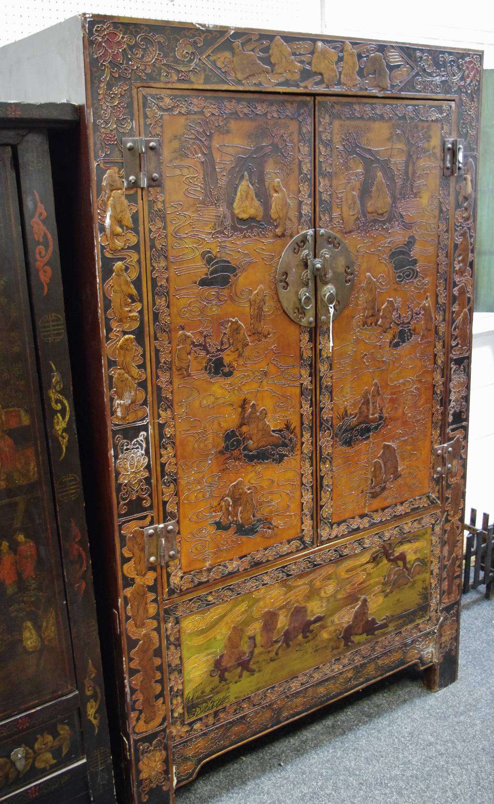 An oriental wardrobe carved with elders and fauna in relief