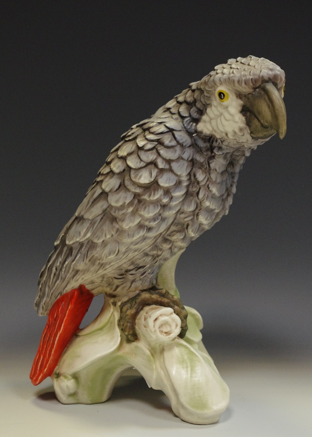 A large Goebel model of a grey parrot, perched on a branch,