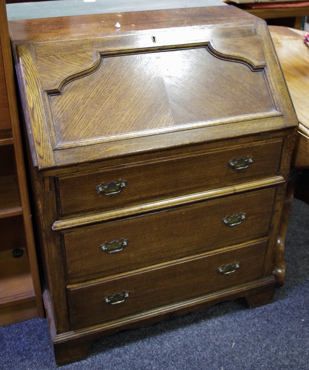 An oak bureau, fall front enclosing associated interior over three graduated drawers, ogee feet.