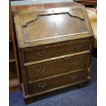 An oak bureau, fall front enclosing associated interior over three graduated drawers, ogee feet.