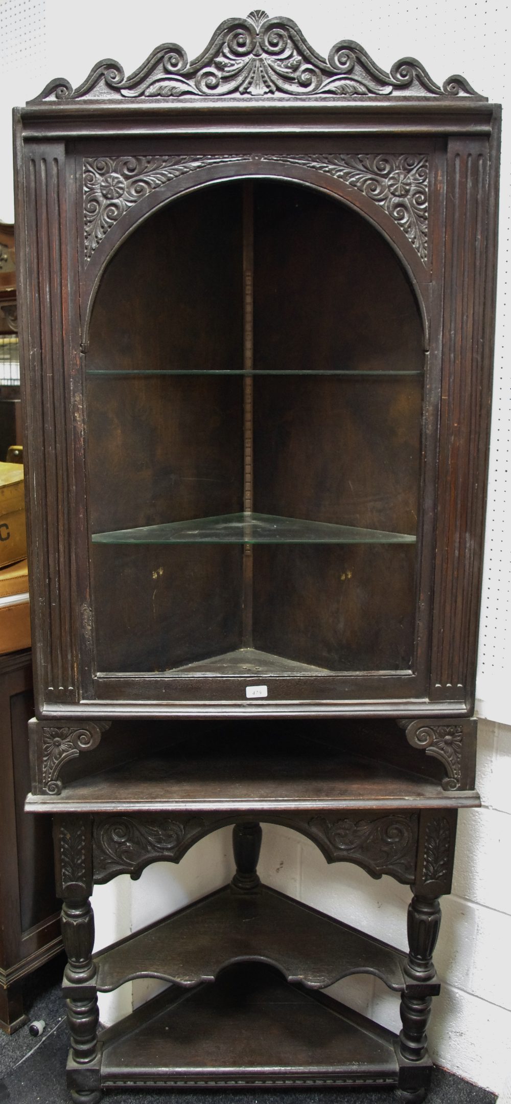 An oak corner cabinet on stand, shaped and carved pediment, two shelves,